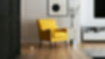 A yellow armchair stands in the centre of a modern living room on a hardwood floor with minimalist pictures and furniture surrounding it. To represent SEO for interior designers.