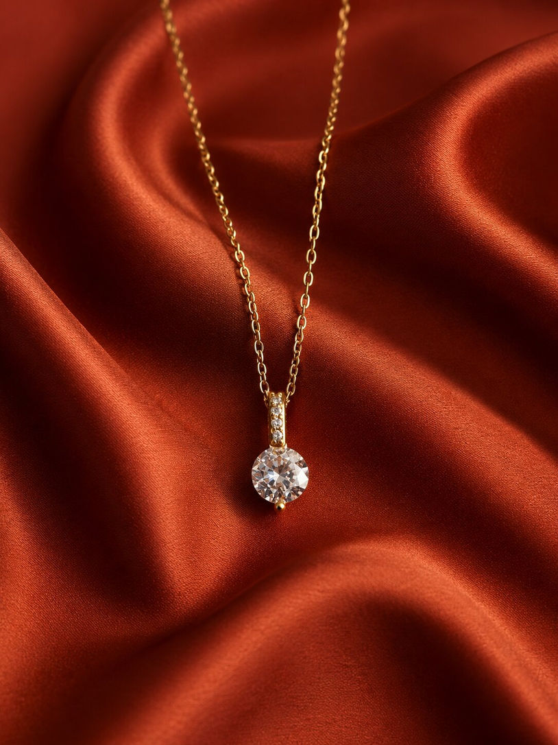 Anti-tarnish gold chain necklace with sparkling solitaire crystal pendant displayed on luxurious satin fabric.