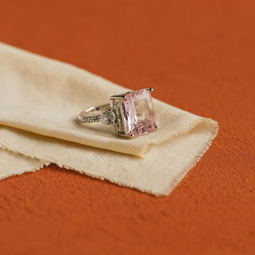 Elegant cushion-cut pink solitaire ring for women with a silver-toned band, displayed on soft beige fabric against a warm ter