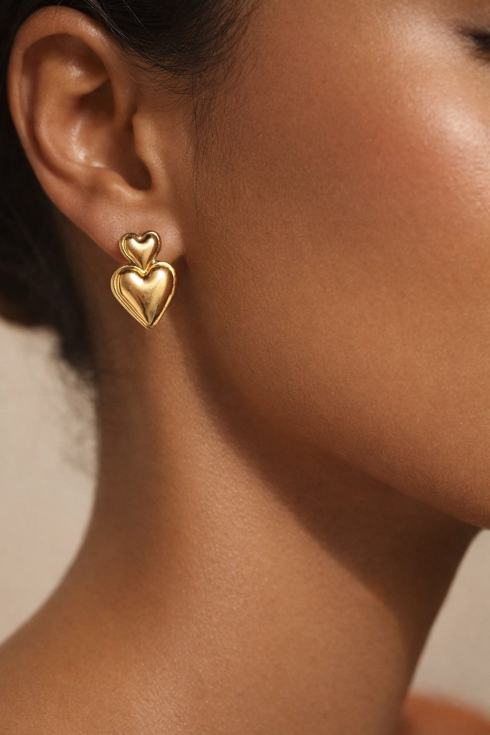 close up studio image of Avantikam Dual Heart stainless steel anti tarnish designer earrings for women India on luxury beige