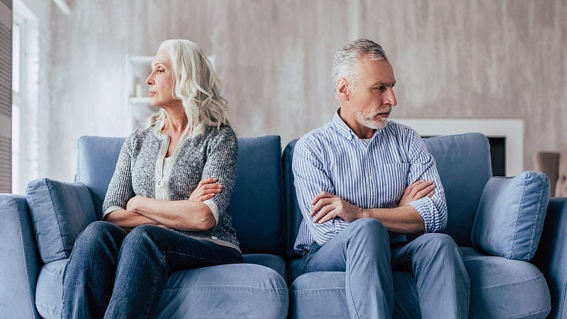 Elderly couple sittting on a couch facing away from each other