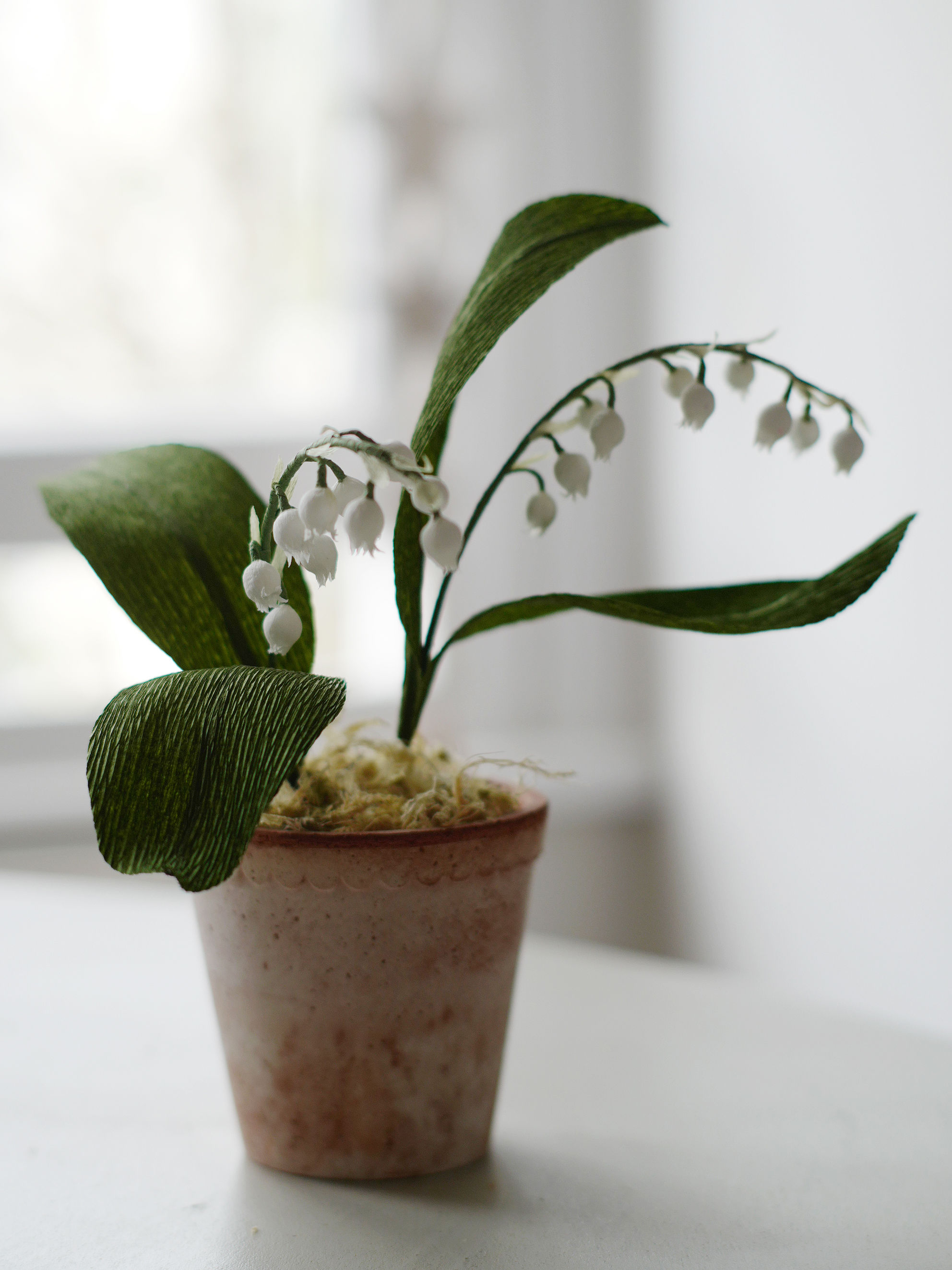 Paper muguets arranged in terra cotta pot