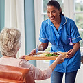 female-care-worker-uniform-bringing-meal-tray-senior-woman-sitting-lounge-home.jpg