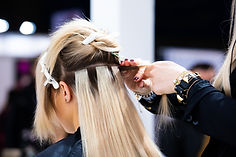 Hair stylist adding hair extensions to a client's hair