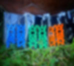 Tre par stora örhängen i blå, grön och orange med ordet "woman"