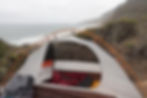 a tent is set up on the edge of a cliff at Point Reyes on the Central California coast, overlooking a misty coastline with surf banging against the cliffs. The tent is white, the poles are orange, and there is a red sleeping bag on an orange sleeping pad contained within