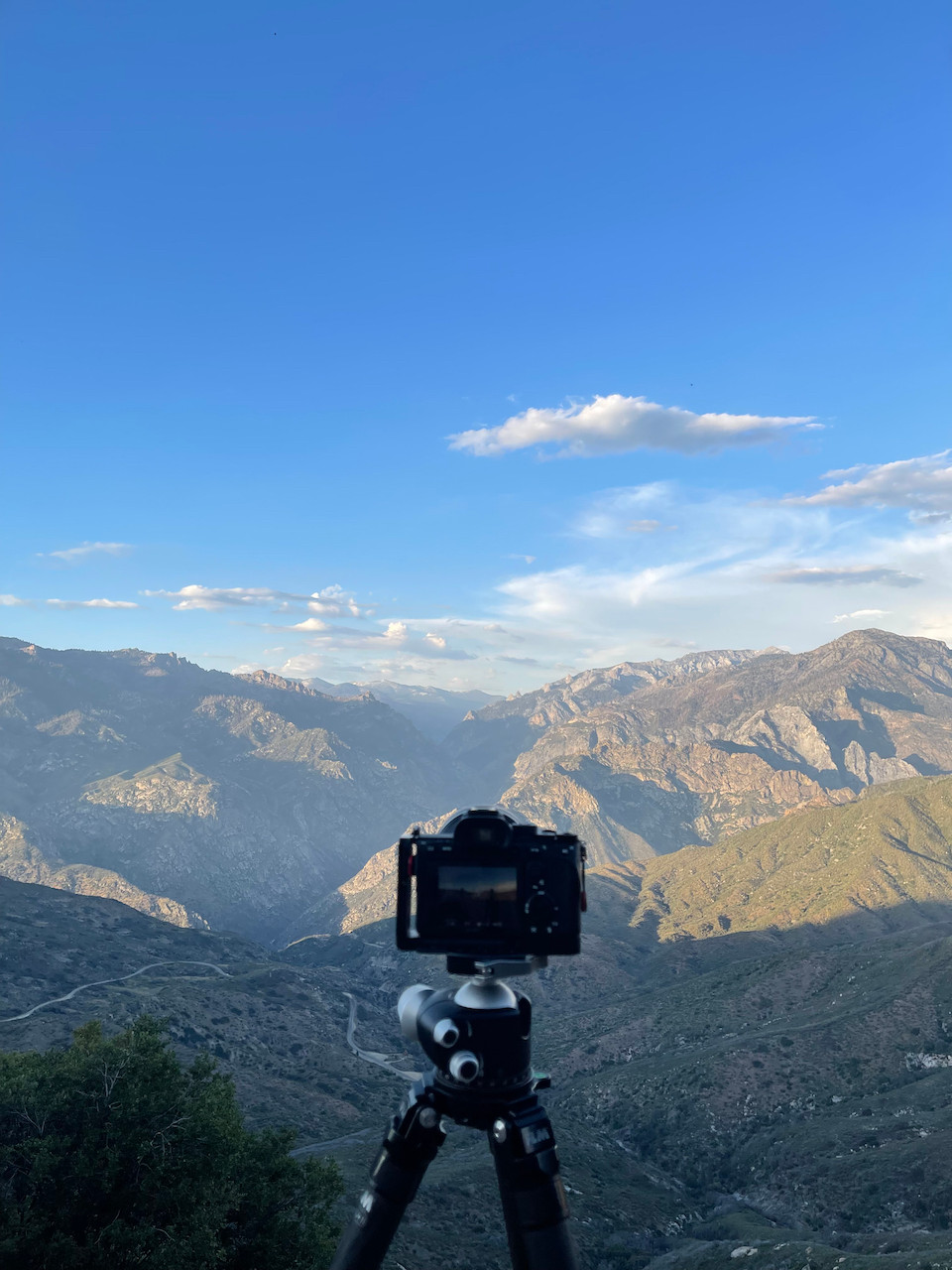 A camera mounted on a tripod stands ready to capture the majesty of the endless mountains stretching out before it