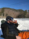 a skiier in full gear sits drinking an apres ski beer at Loon Mountain in Lincoln New Hampshire