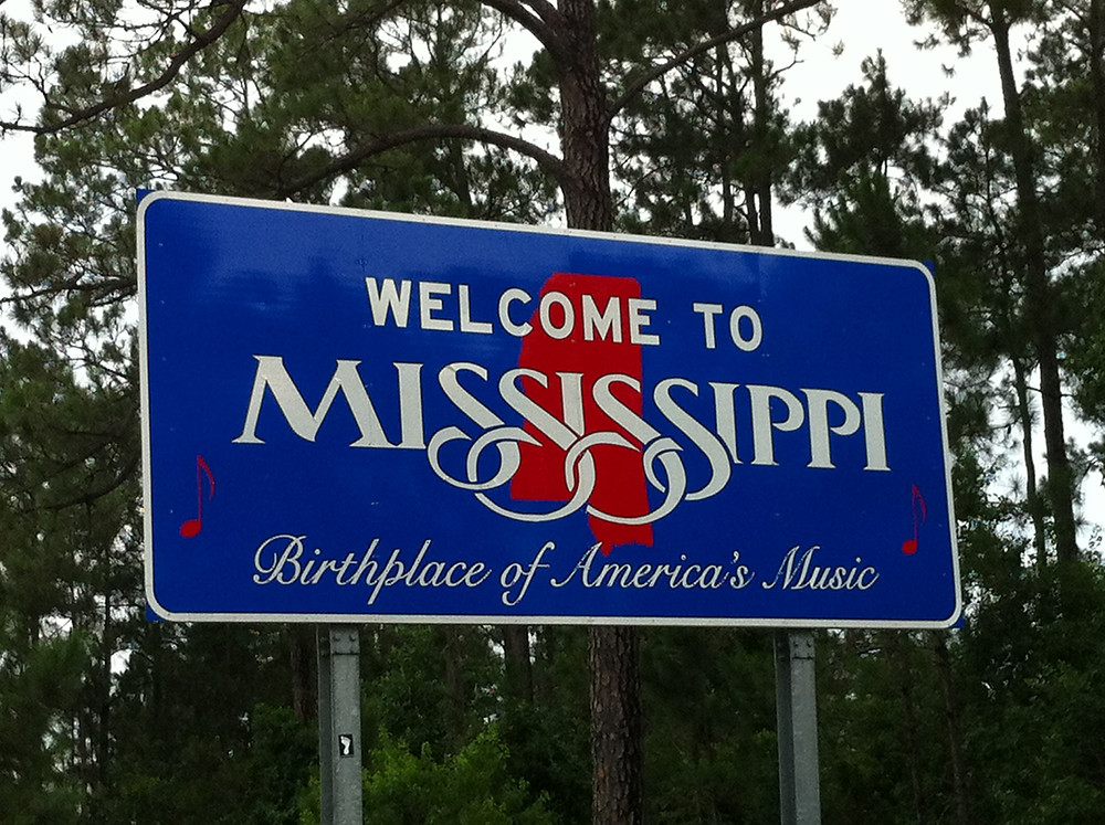 A blue highway sign welcoming travelers to Mississippi, the "Birthplace of America's Music" (move over, New Orleans, Chicago, New York, and everywhere else America's music was born)