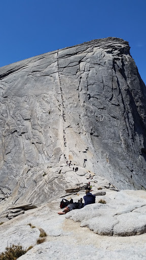 Action shot of the final ascent of Half Dome in Yosemite National Park. Climbers use ropes and wood planks to climb up the last 400 feet or so of the grueling hike