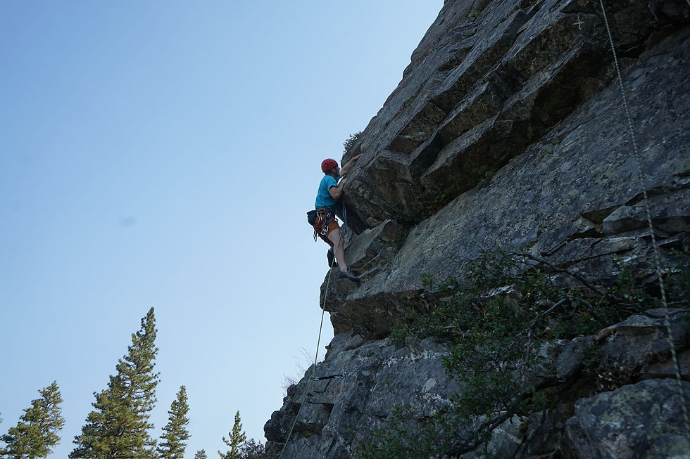 A climber in a blue shirt has just a little farther to go to reach the top of the rock at The Emeralds near Lake Tahoe, California