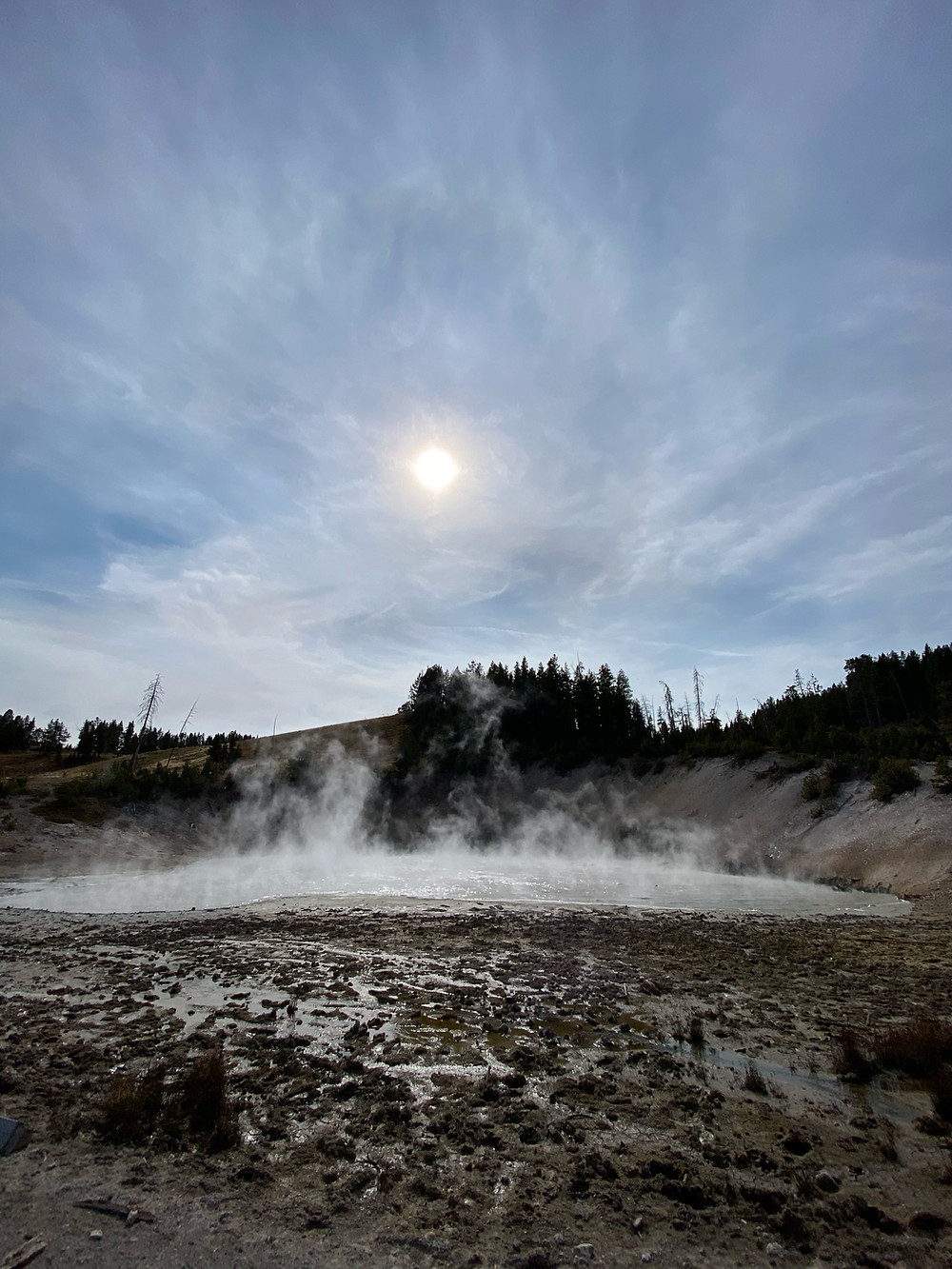Geyser smoking in Yellowstone National Park, partially obscuring the sun directly overhead