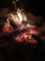 a fire rages brightly and hotly, flames pouring out of the glowing coals. This fire is hot and ready for the backpacking meal to begin.