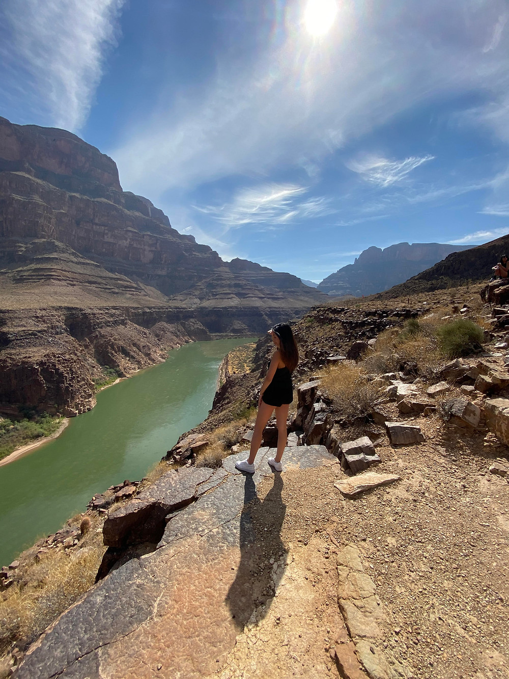 A woman gazes out over the green river and brown rocks of the Grand Canyon in Arizona