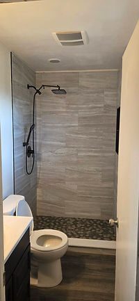 Walk-in shower remodel with gray tile and black rainfall shower fixtures