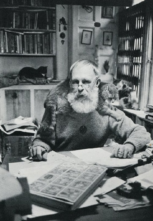 Black and white photograph of artist edward gorey surrounded by cats in his office