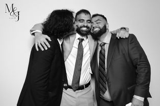 Wedding guests hugging and smiling in a black and white glam photo booth portrait.
