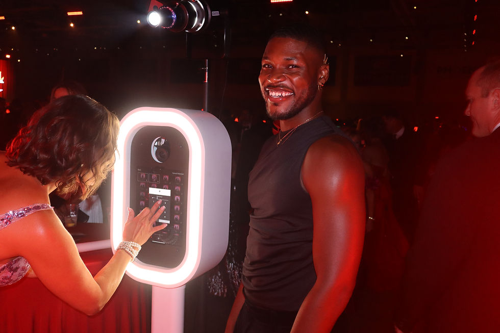 Lead Experience Specialist Devin assisting a guest at the Spotlight Booth during The Capital Gala in Baton Rouge, surrounded by red ambient lighting.