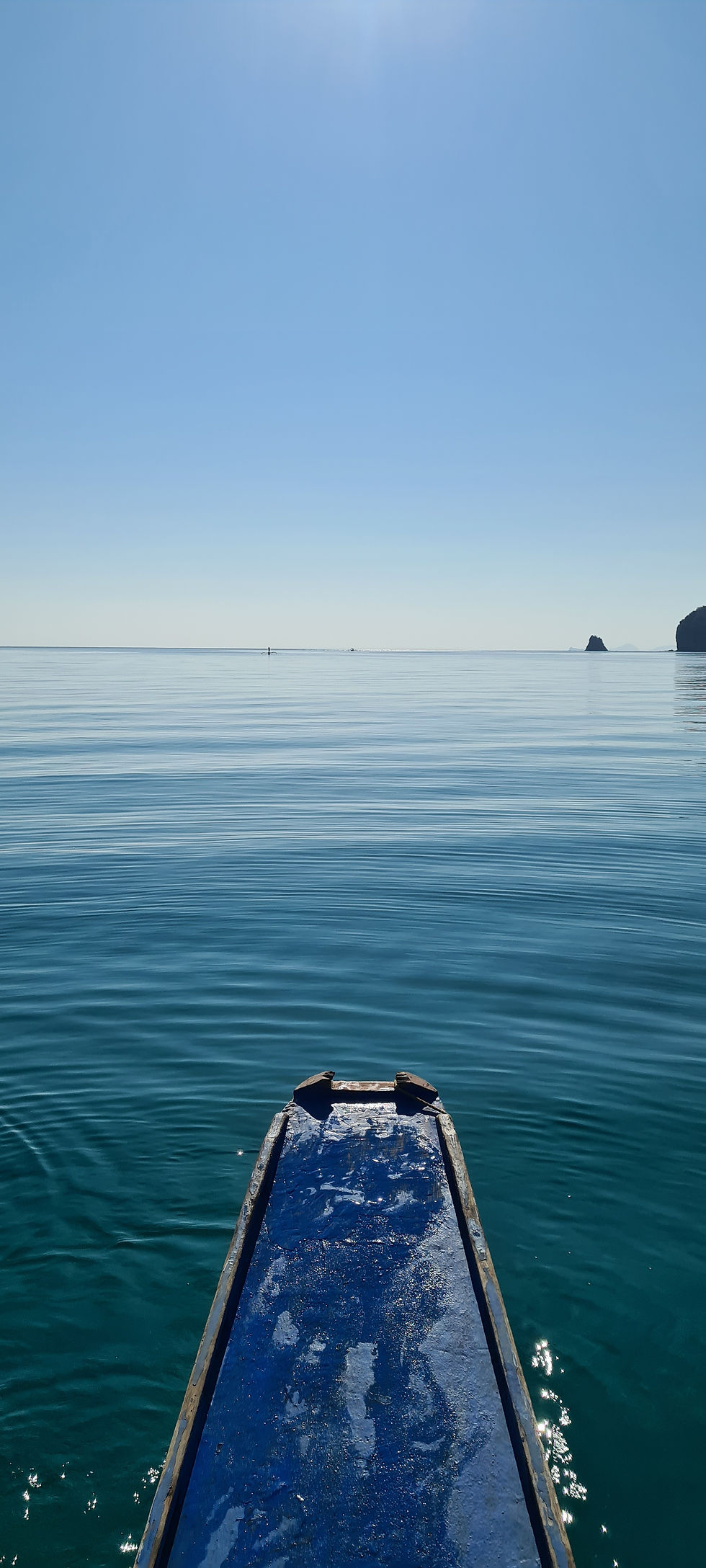 The front of a small boat facing a calm ocean