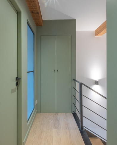 Photographie de la rénovation d'un couloir, sol parquet bois, mur vert profond, verrière et poignée en métal, poutre bois. Par l'agence 9 février architetcure intérieure à Vichy