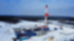 Red and white oil drilling rig in a snowy landscape.