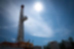 Oil drilling rig tower against a bright blue sunny sky