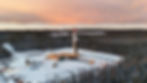 Aerial view of a drilling rig in a snowy forest at sunset