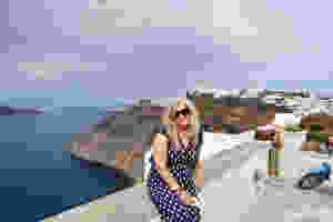 Siri Kay Jostad of Wander Away with Siri Kay sitting on a wall with a view of the caldera in Santorini Greece