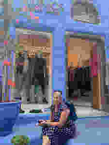 Siri Kay Jostad of Wander Away with Siri Kay sitting in front of a shop in Fira Santorini Greece