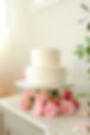 Two-tier white cake on a bed of pink wedding and event florals.