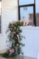 Pink roses and greenery wedding and event florals on a bar.