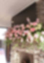 Pink and white wedding and event florals on a fireplace mantel.