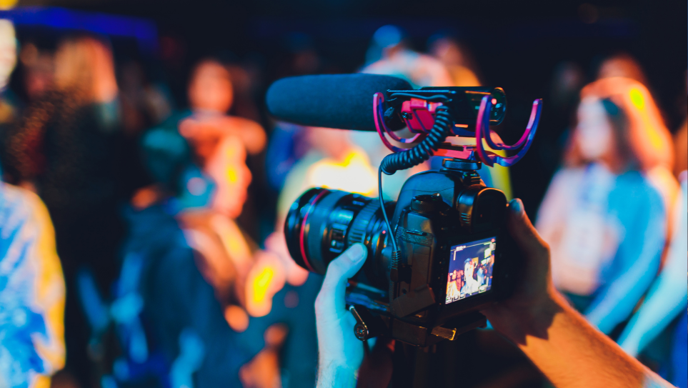 A videographer filming delegates at a hybrid event.