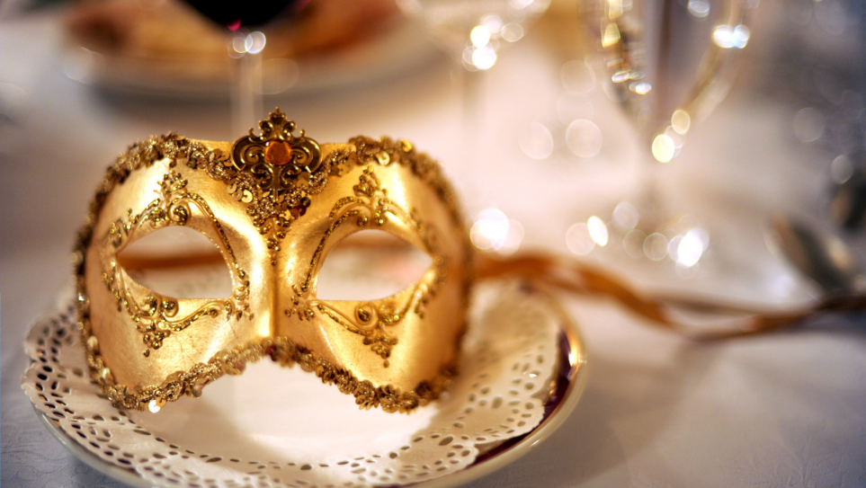 A gold eye mask with ribbon ties on a place setting or corporate themed events.