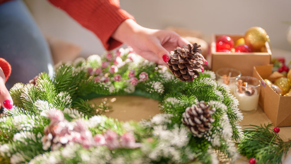 A pair of female hands making a Christmas wreath.