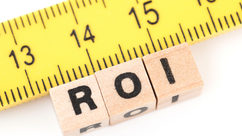 A yellow tape measure and three small wooden blocks with the letters R O I on them, representing measuring event ROI