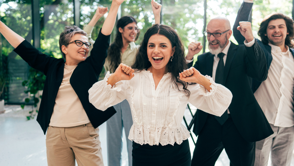Five male and female delegates of different ages smiling, cheering and air punching for the conference trends for 2026.