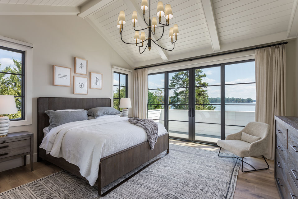 Primary bedroom with lakefront views, chandelier, and neutral tones in South Carolina lakeside home