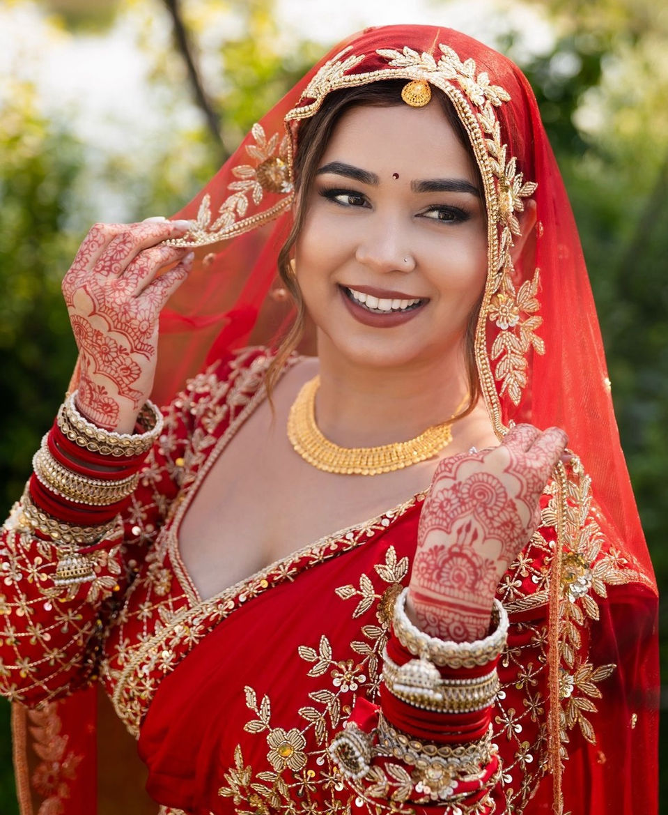 Smiling Indian bride in red and gold wedding attire