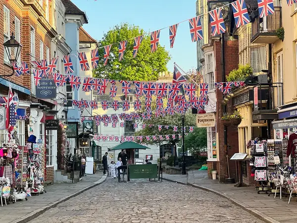 The charming cobbled streets of Windsor town centre decorated with Union Jack flags, a key destination for Crownwood Charters' luxury chauffeur service and private venue transfers in Berkshire.