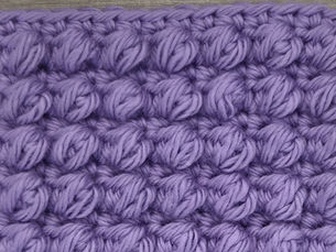 Close-up of purple yarn crocheted in the Puff stitch, showing rows of soft, raised seven loop puffs.