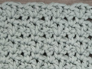 Close-up of yarn crocheted in the Blossom stitch, showing alternating rows of V-shaped Double Crochet pairs and Single Crochet stitches.