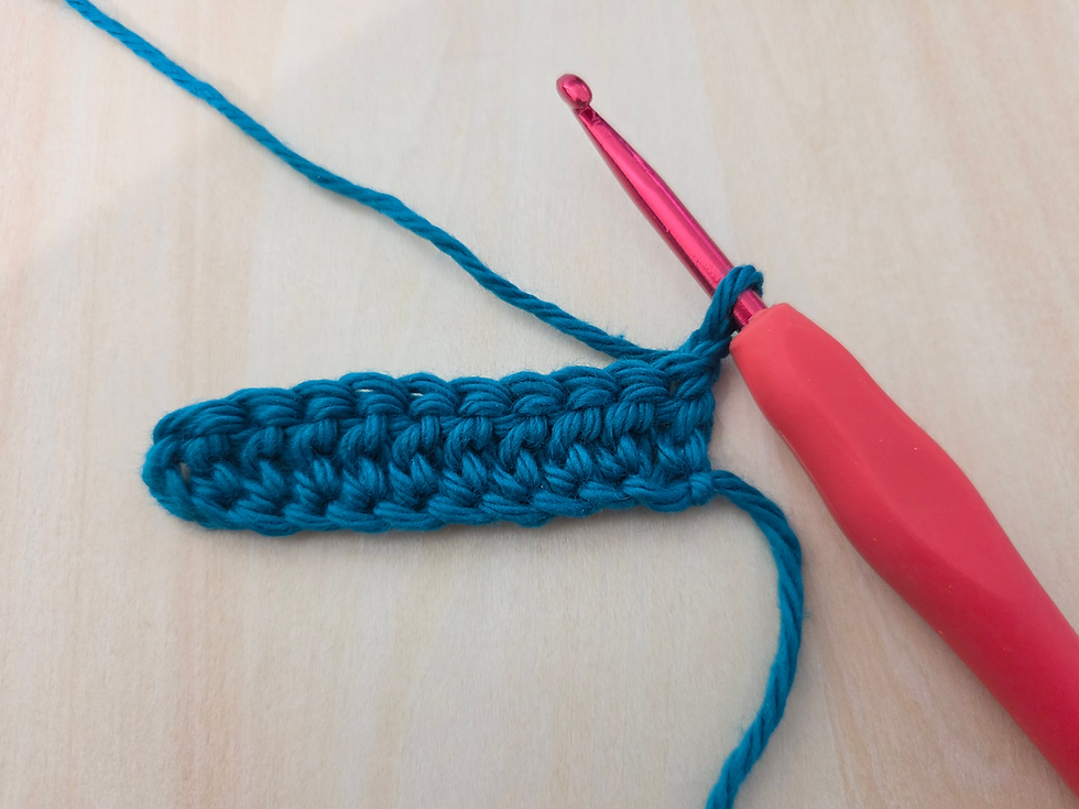 Row of teal Double Crochet stitches with a crochet hook.