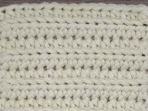Close-up of cream yarn worked in rows of Back Loop Half Double Crochet stitches.