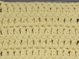Close-up of yellow yarn worked in rows of Double Crochet stitches