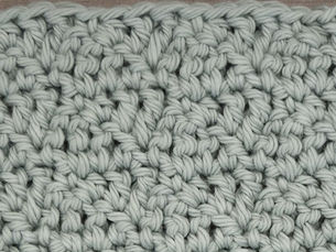 Close-up of yarn crocheted in the Compact Triangles stitch, showing repeating triangular stitch formations.