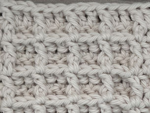 Close-up of yarn crocheted in the Waffle stitch, showing a raised grid of recessed square sections.