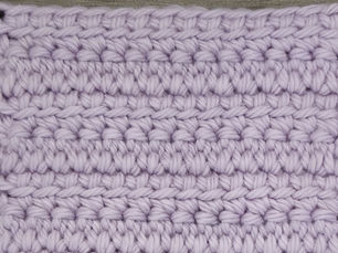 Close-up of yarn worked in dense rows of Linked Double Crochet stitches.