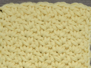 Close-up of yarn worked in the Wattle Stitch with grouped Single crochet, chain and Double Crochet stitches.