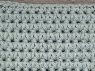 Close-up of yarn crocheted in the Single Crochet Spike stitch, showing elongated stitches extending into the row below.